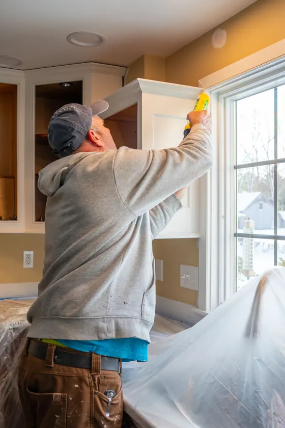 Craftsman caulking a newly installed kitchen cabinet