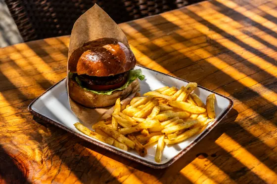 Burger and fries on a sunlit wooden table